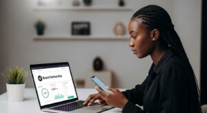 An influencer in a modern indoor setting reviewing a collaboration on a laptop while holding a smartphone